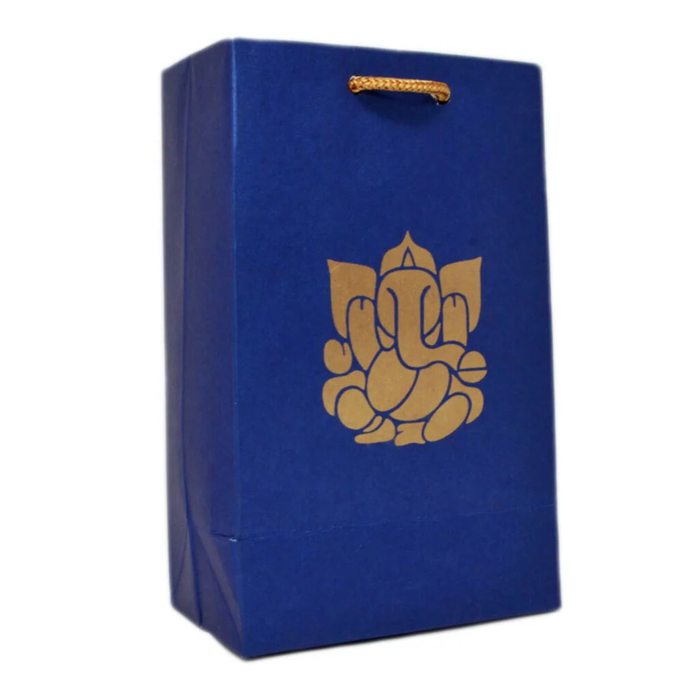 A royal blue paper gift bag with a gold foil Ganesha graphic on the front and a gold hanging loop handle, shown on a plain white background.