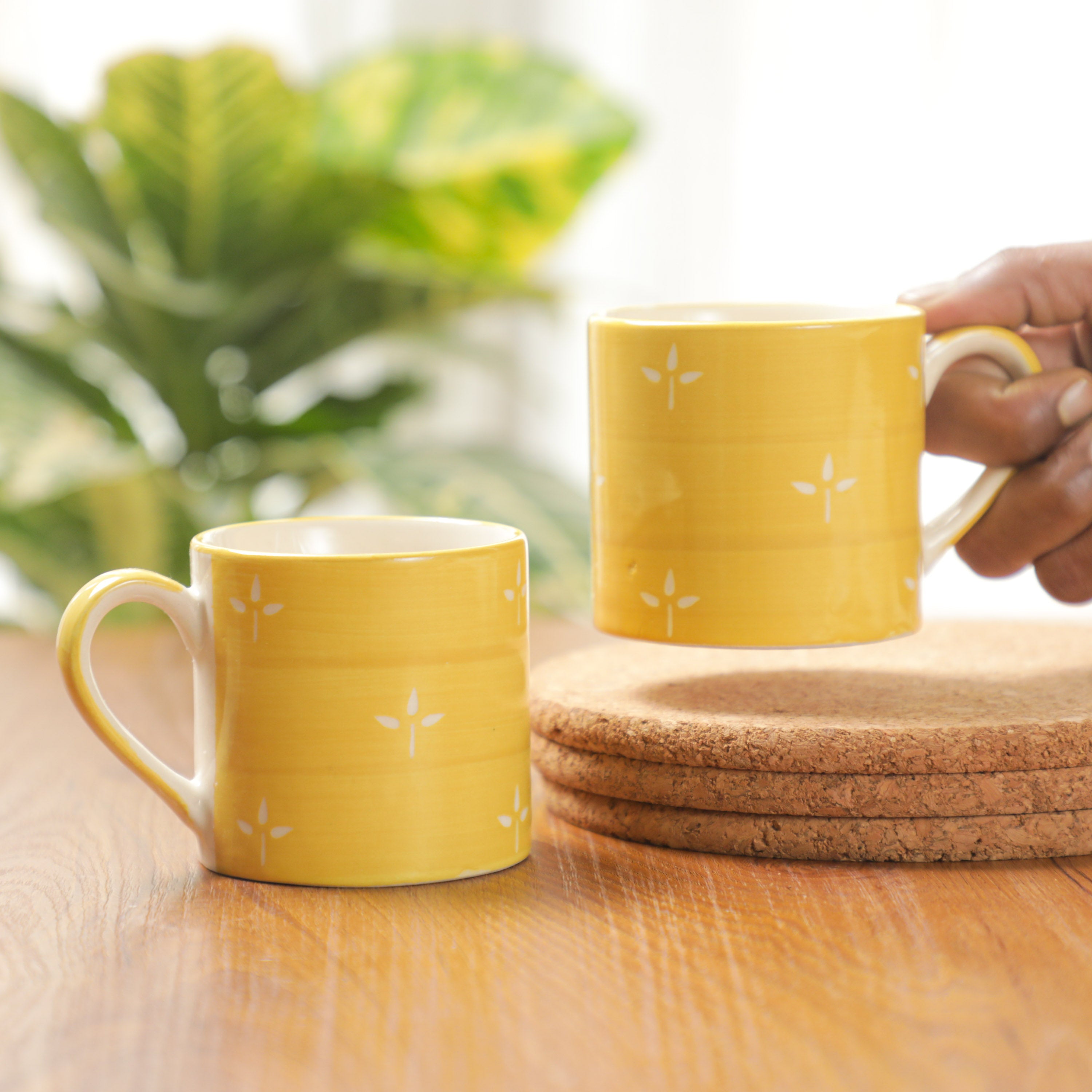 person holding bright Yellow Tea Cups
