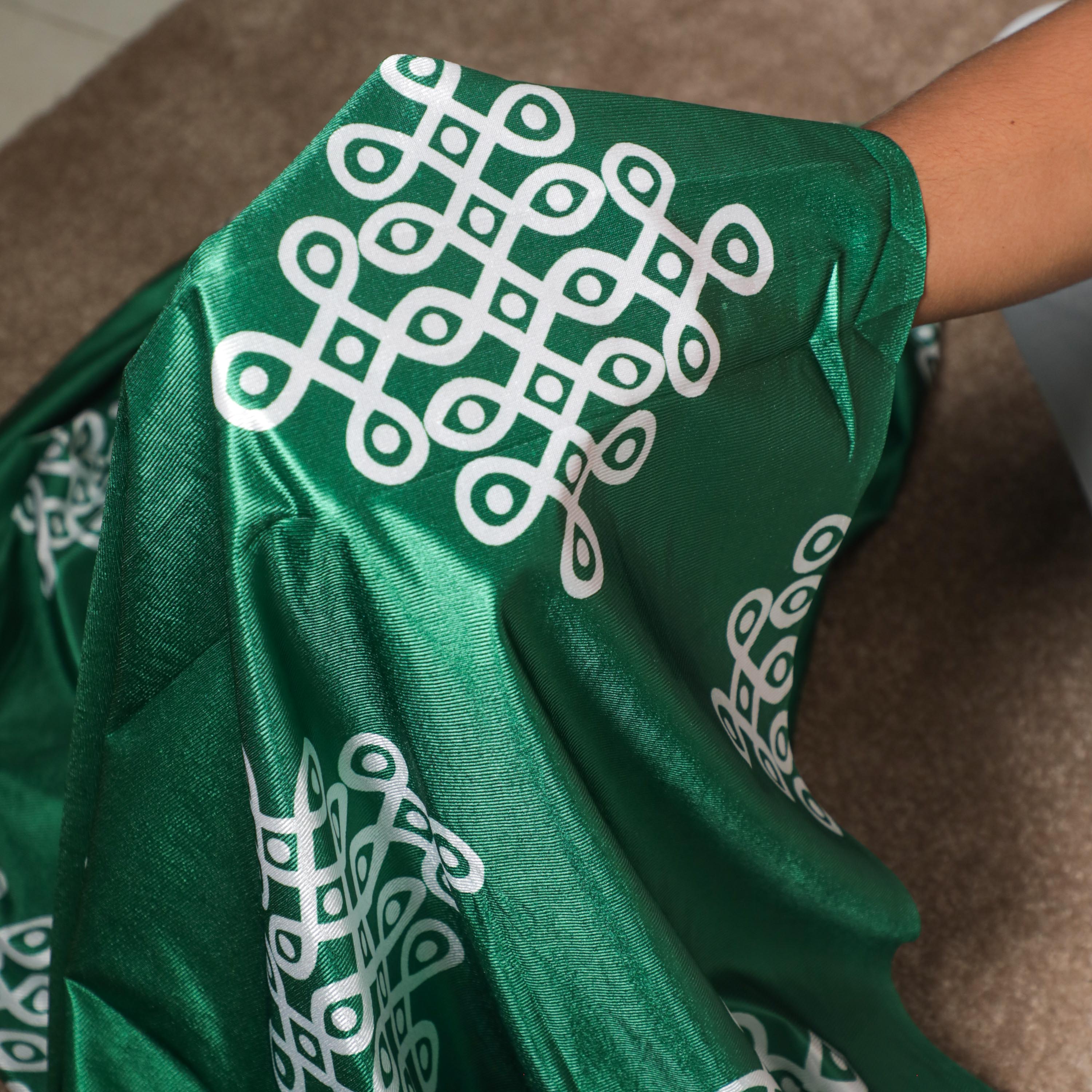 White kolam design on the green backdrop cloth