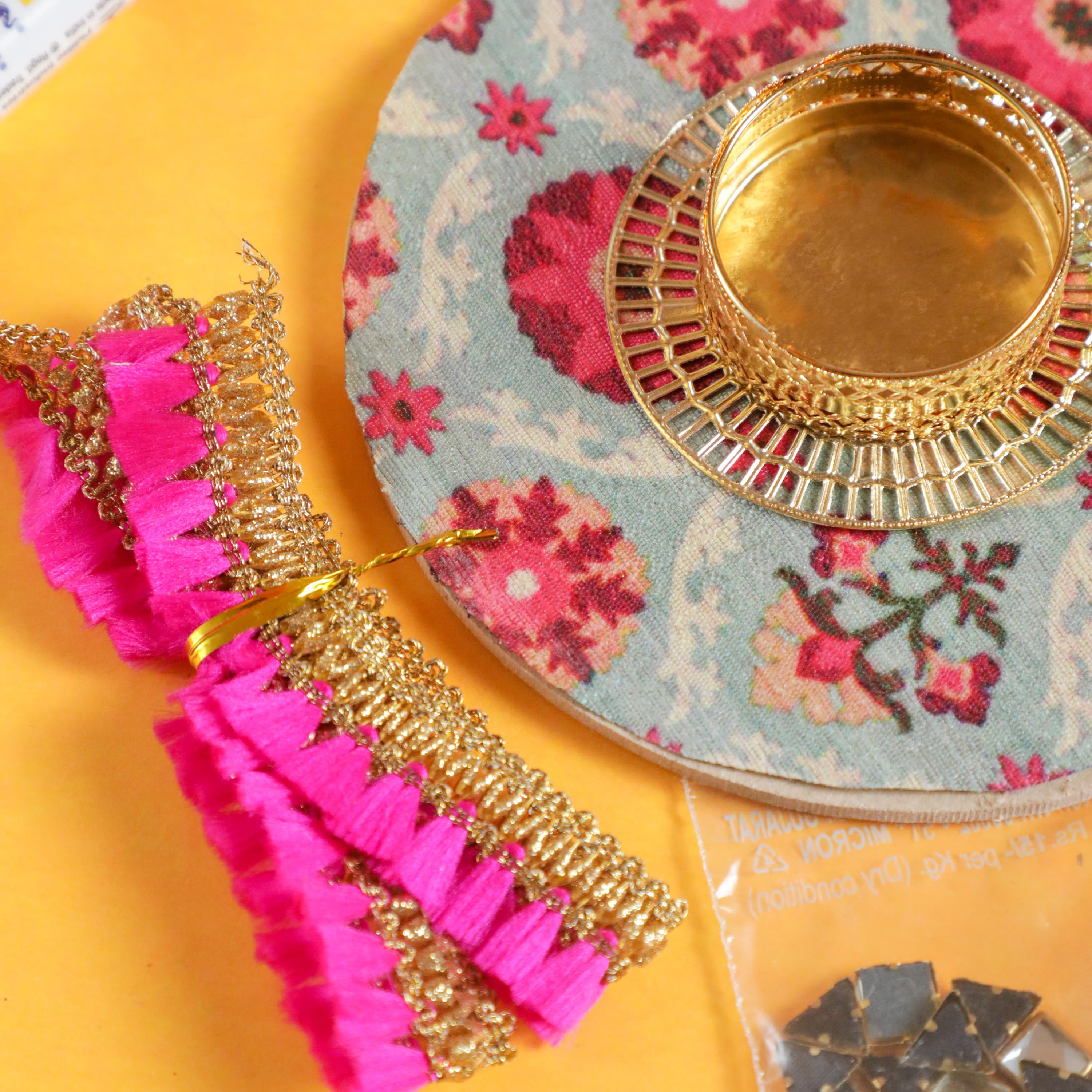A pink lace with round metal diya holder for diwali