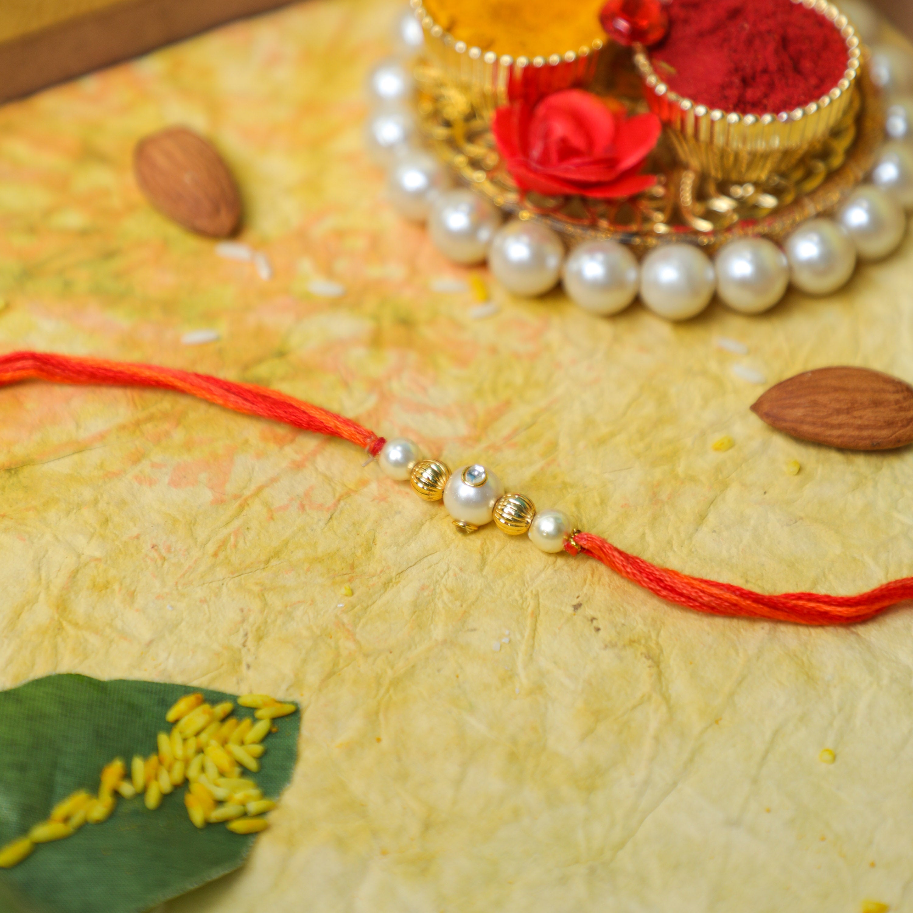 Pastel Orange Thread Rakhi with Pearl and Gold Balls