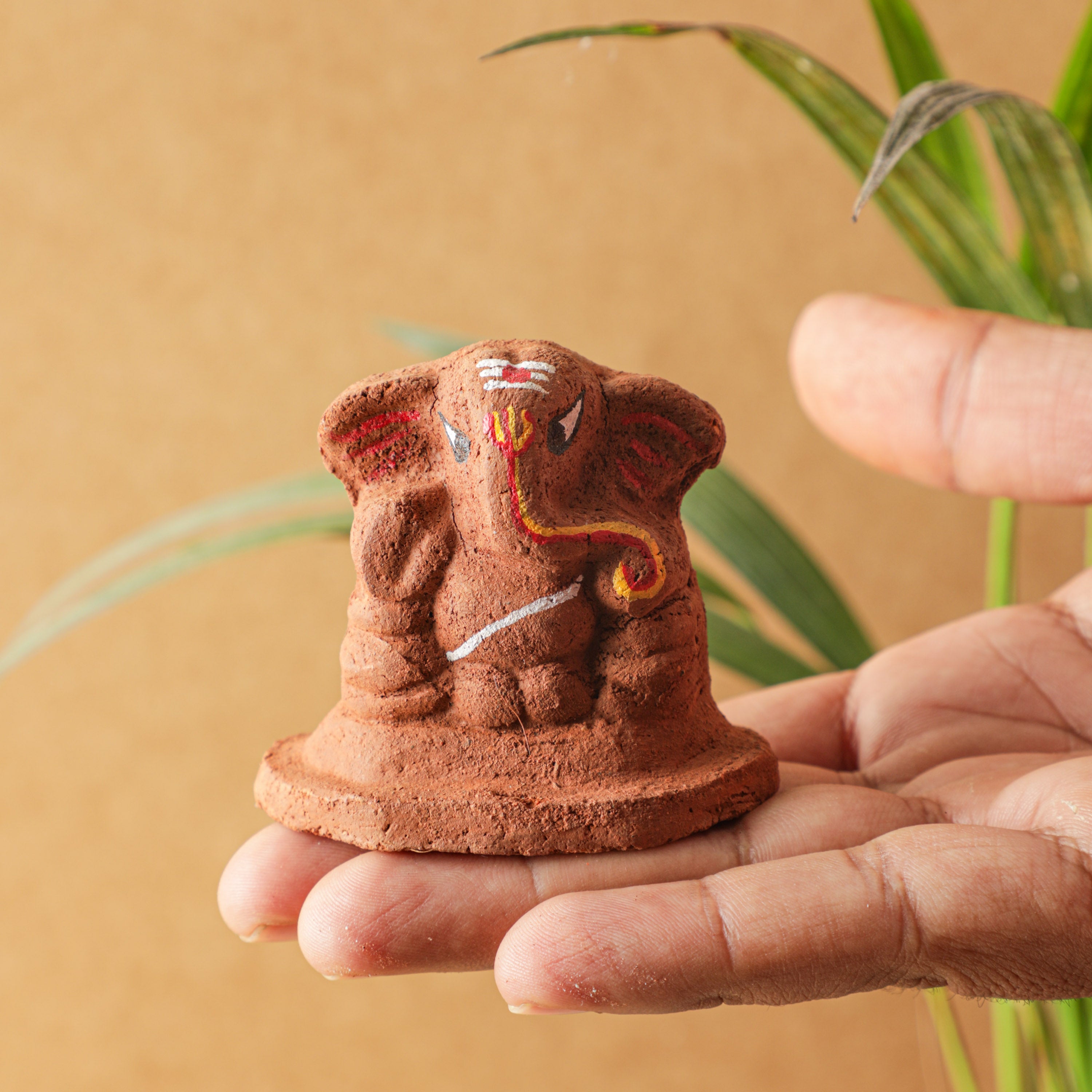 Holding the clay ganesha in hand by an artist