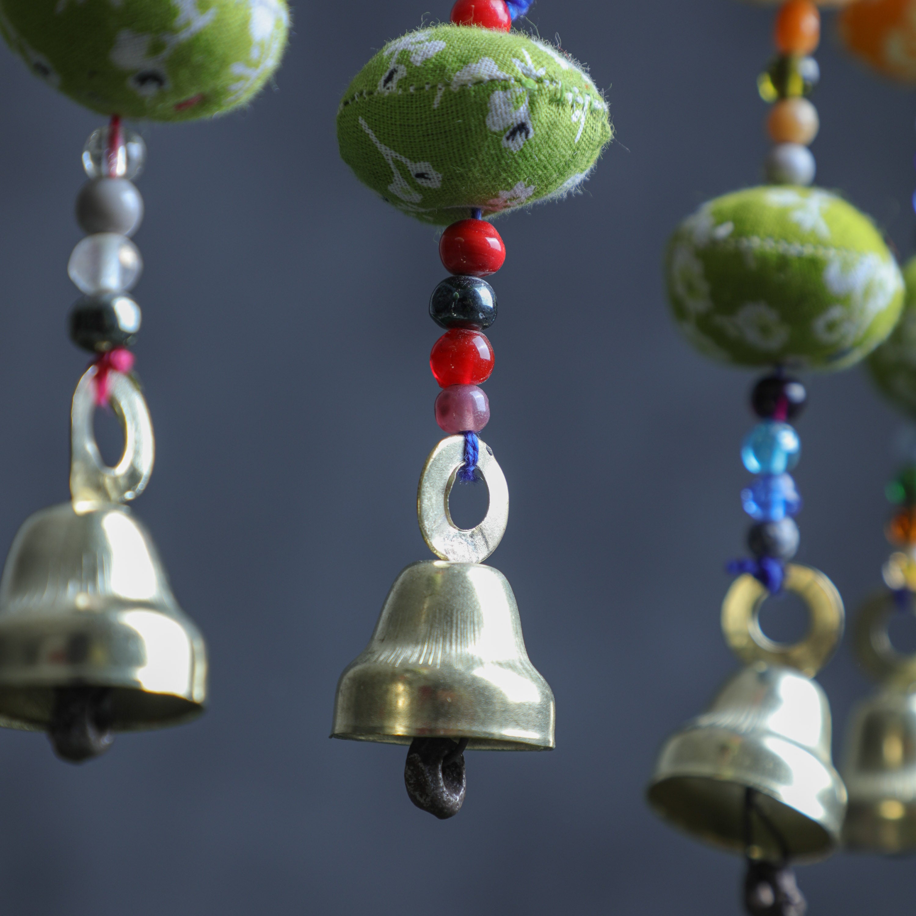 A fabric bandhini hangings with a bell at the end